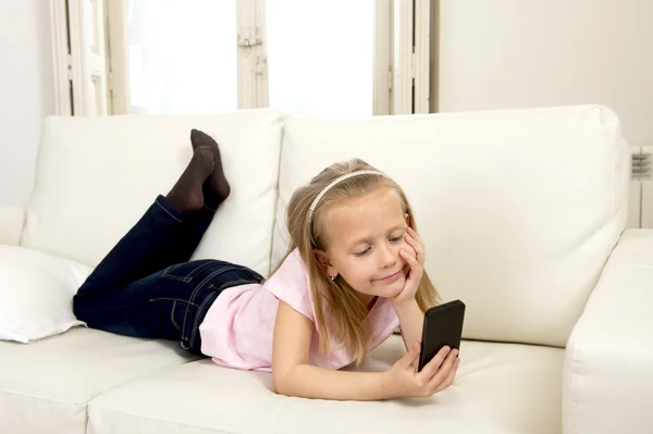 Menina loira feliz em casa sofá usando o aplicativo de internet no telefone móvel — Fotografia de Stock