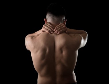 young muscular sport man holding sore neck massaging cervical area suffering body pain