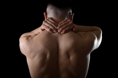 young muscular sport man holding sore neck massaging cervical area suffering body pain