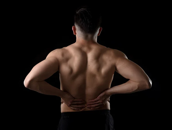 Young muscular body sport man holding sore low back waist with his  hands  suffering pain in athlete stress — Stock Photo, Image