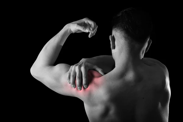 Young muscular sport man holding sore shoulder in pain touching massaging in workout stress — Zdjęcie stockowe