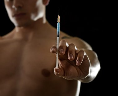 young athletic sportsman holding syringe in sport doping and cheat concept