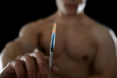 young athletic sportsman holding syringe in sport doping and cheat concept