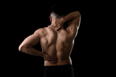 back view of young man with muscular body holding his neck and low back suffering spinal pain