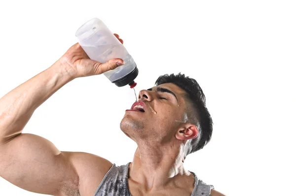 Jovem atlético esporte homem sedento beber água segurando garrafa derramando fluido no rosto suado — Fotografia de Stock