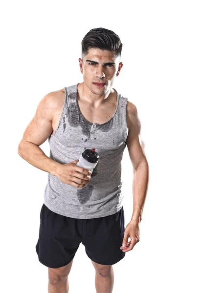 Young athletic sport man thirsty holding bottle of water with sweaty face and wet singlet — Stock Photo, Image