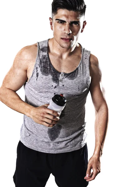 Молодий спортивний чоловік спраглий тримає пляшку води з спітнілим обличчям і мокрим синглом — стокове фото