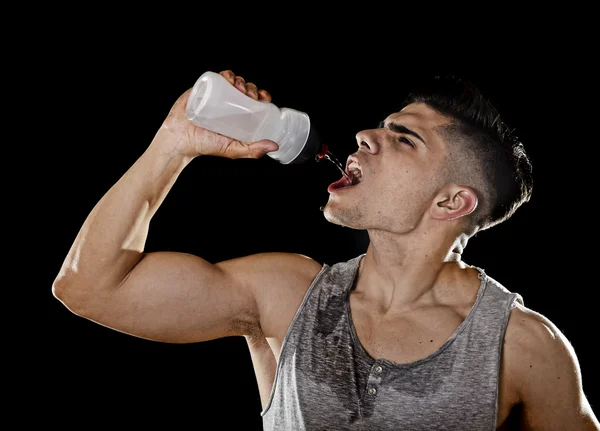 Jeune sportif homme assoiffé d'eau potable tenant bouteille versant fluide sur le visage suant — Photo