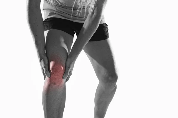 Jonge sport vrouw met sterke atletische benen houden van de knie met handen in pijn lijden ligament letsel — Stockfoto