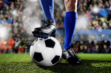 futbol stadyumunda maç oynarken topu ile ayakta mavi çorap ve siyah ayakkabı futbolcunun bacak ve ayakları