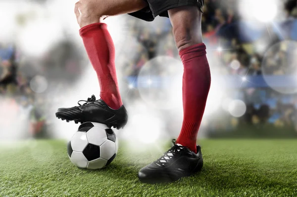 Jogador de futebol em meias vermelhas e sapatos pretos entranhando com a bola em pé no campo do estádio — Fotografia de Stock