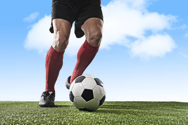 Pernas de jogador de futebol em meias vermelhas e sapatos pretos correndo e driblando com bola jogando ao ar livre — Fotografia de Stock