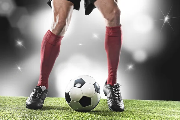 Jogador de futebol em meias vermelhas e sapatos pretos correndo e driblando com a bola jogando no estádio — Fotografia de Stock