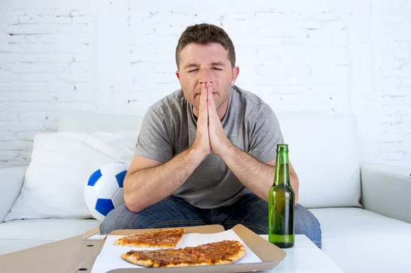 Mladý muž sám ve stresu sledovat fotbalový zápas v televizi se modlí, nervózní a vzrušená — Stock fotografie