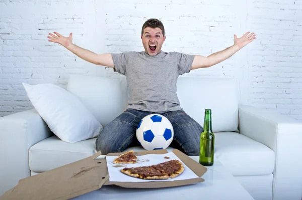 Человек празднует гол на домашнем диване смотреть футбол по телевизору — стоковое фото