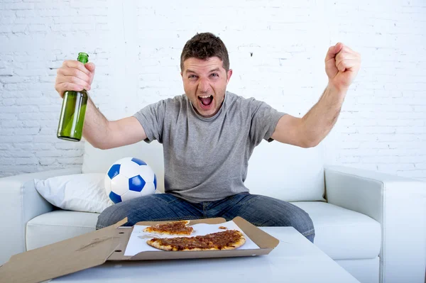 Человек празднует гол на домашнем диване смотреть футбол по телевизору — стоковое фото