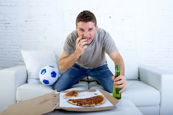 Молодой человек смотрит футбол по телевизору нервничает и взволнован страдая от стресса грызть ногти на диване — стоковое фото
