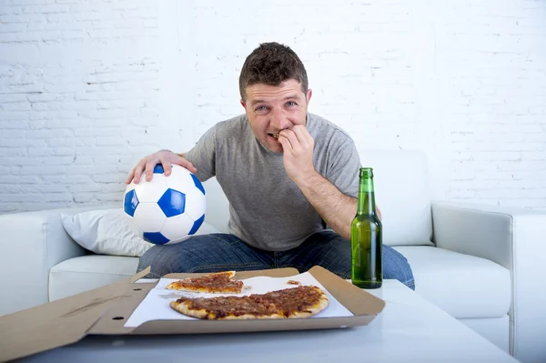 Young man watching football game on television nervous and excited suffering stress biting fingernail on sofa — Stock fotografie