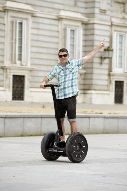young happy tourist man riding city tour segway driving happy and excited visiting Madrid palace