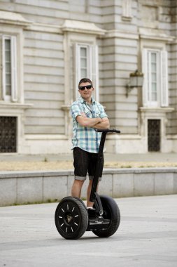 young happy tourist man riding city tour segway driving happy and excited visiting Madrid palace