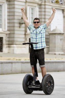 young happy tourist man riding city tour segway driving happy and excited visiting Madrid palace