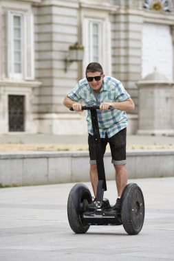 young happy tourist man riding city tour segway driving happy and excited visiting Madrid palace