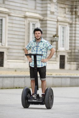 young happy tourist man wearing safety helmet headgear riding city tour segway driving happy