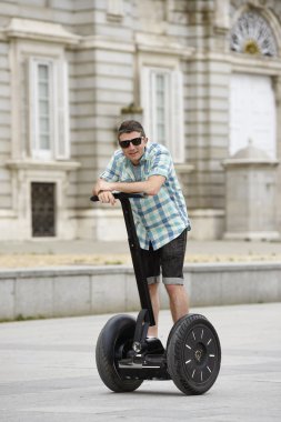 young happy tourist man riding city tour segway driving happy and excited visiting Madrid palace