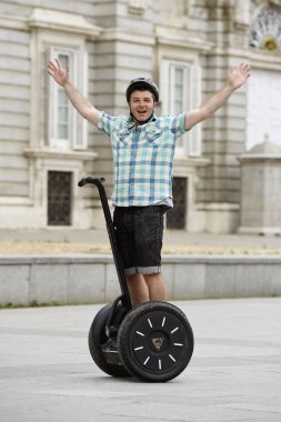 young happy tourist man wearing safety helmet headgear riding city tour segway driving happy