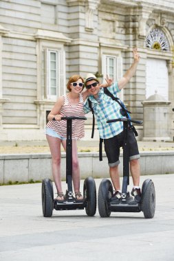 young happy tourist couple riding segway enjoying city tour in Madrid palace in Spain having fun driving together 