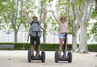 young happy tourist couple riding segway enjoying city tour in Madrid park in Spain together 