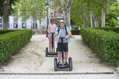 young happy tourist couple riding segway enjoying city tour in Madrid park in Spain together 