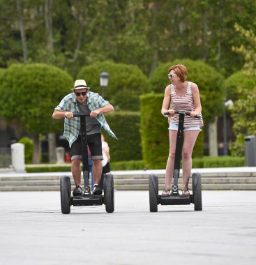 young happy tourist couple riding segway enjoying city tour in Madrid park in Spain together 