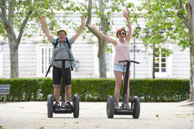 young happy tourist couple riding segway enjoying city tour in Madrid park in Spain together 