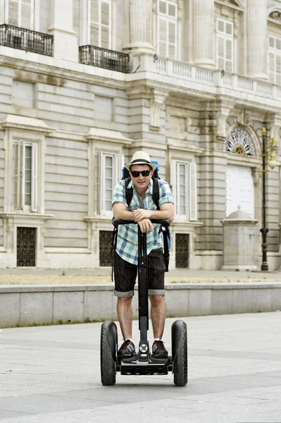 Young happy tourist man with backpack riding city tour segway driving happy and excited visiting Madrid palace — стокове фото