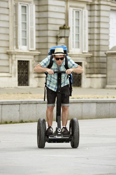 Young happy tourist man with backpack riding city tour segway driving happy and excited visiting Madrid palace — Stock Fotó