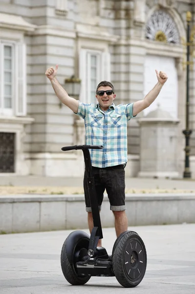 Young happy tourist man riding city tour segway driving happy and excited visiting Madrid palace — стокове фото
