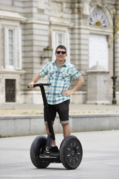 Young happy tourist man riding city tour segway driving happy and excited visiting Madrid palace — Zdjęcie stockowe