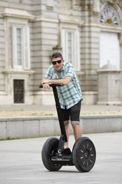 Young happy tourist man riding city tour segway driving happy and excited visiting Madrid palace — стокове фото