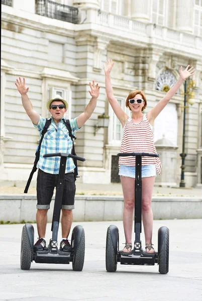 Young happy tourist couple riding segway enjoying city tour in Madrid palace in Spain having fun driving together — Zdjęcie stockowe