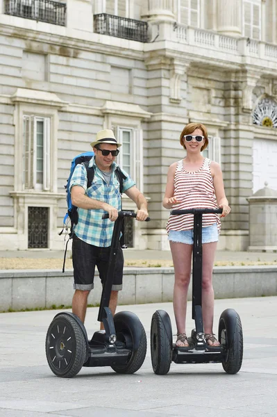 Young happy tourist couple riding segway enjoying city tour in Madrid palace in Spain having fun driving together — Stock Fotó