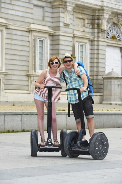 Young happy tourist couple riding segway enjoying city tour in Madrid palace in Spain having fun driving together — Stock Fotó