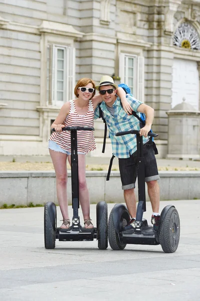 Young happy tourist couple riding segway enjoying city tour in Madrid palace in Spain having fun driving together — Stok fotoğraf
