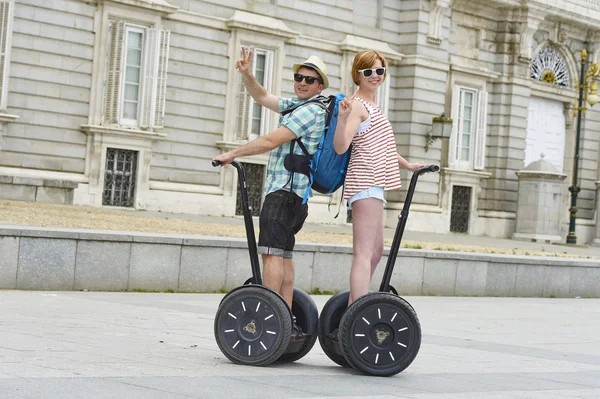 Young happy tourist couple riding segway enjoying city tour in Madrid palace in Spain having fun driving together — Zdjęcie stockowe