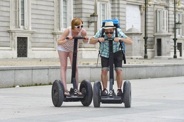 Young happy tourist couple riding segway enjoying city tour in Madrid palace in Spain having fun driving together — Stockfoto