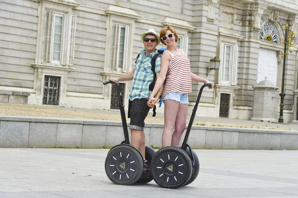 Young happy tourist couple riding segway enjoying city tour in Madrid palace in Spain having fun driving together — Stockfoto