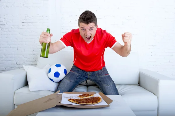 Muž, který sleduje fotbal v televizi v týmu Jersey oslavovat cíl šílený šťastný skok na pohovku — Stock fotografie