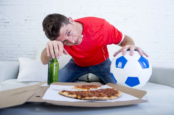 Hombre sosteniendo la bola y la botella de cerveza viendo partido de fútbol en la televisión abatido triste y decepcionado por el fracaso o la derrota —  Fotos de Stock