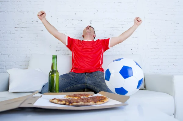 Νέο ποδόσφαιρο ανεμιστήρα άνθρωπος βλέποντας την παιχνίδι στην τηλεόραση σε ομάδα ζέρσεϊ εορτασμού στόχος τρελό ευτυχισμένος στον καναπέ — Φωτογραφία Αρχείου