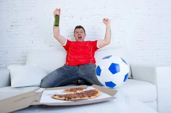 Jonge voetbal fan man kijken wedstrijd op tv in team jersey vieren doel gek gelukkig op Bank — Stockfoto